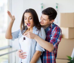young-adult-couple-inside-room-with-boxes-holding-new-house-keys-banner