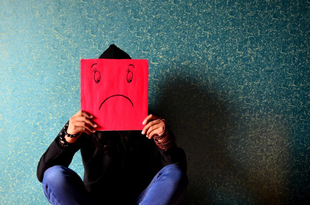 deprese muž držící masku smutného smajlíka