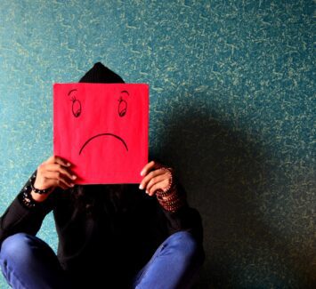 deprese muž držící masku smutného smajlíka